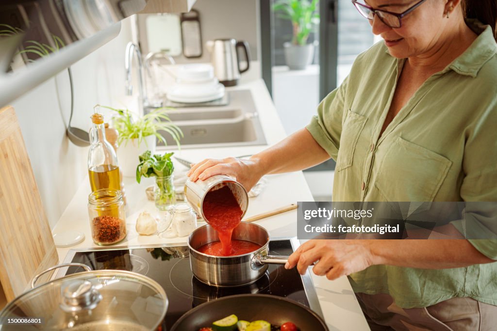 Frau in der Küche, die Tomatensauce zubereitet