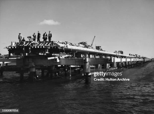 Group of men stand on a Kwinana oil refinery jetty, under construction at sea, Western Australia, November 1954.