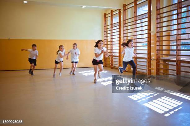 schulkinder laufen während des sportunterrichts - school sports stock-fotos und bilder