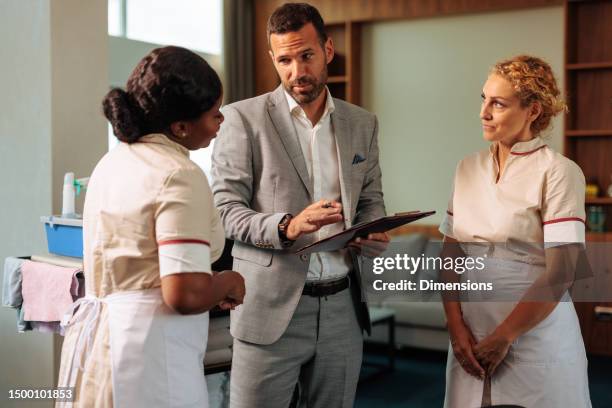 staff manager talking with two diverse housekeepers - cleaner man uniform stock pictures, royalty-free photos & images