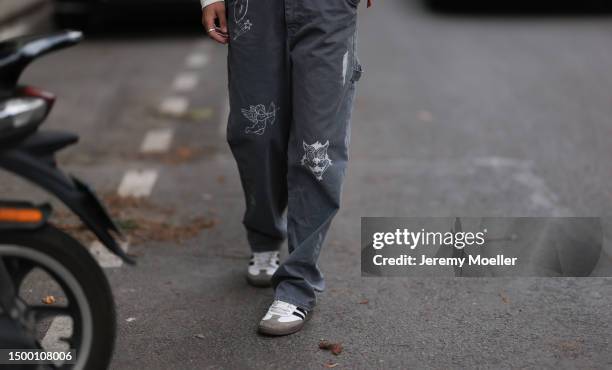 Fashion Week guest is seen wearing Adidas Samba white and black sneaker, grey denim wide leg pants, silver chain, black crossbody leather bag and...
