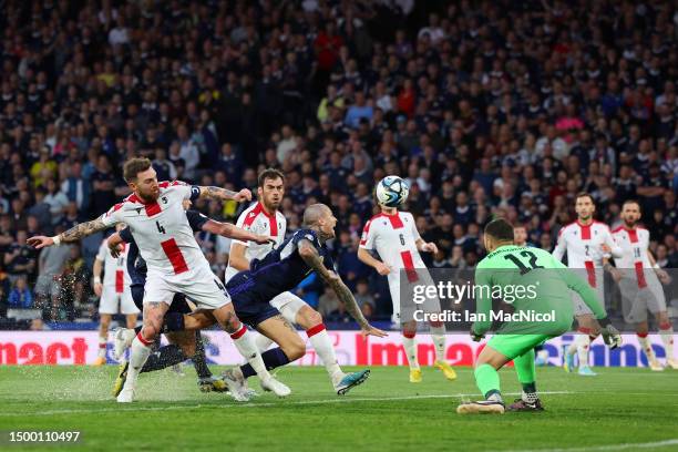 Lyndon Dykes of Scotland shoots whilst under pressure from Guram Kashia of Georgia during the UEFA EURO 2024 qualifying round group A match between...