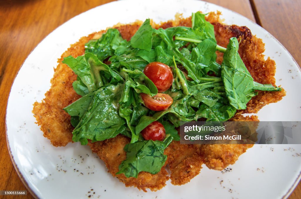 Chicken Milanese topped with arugula leaves and grape tomatoes