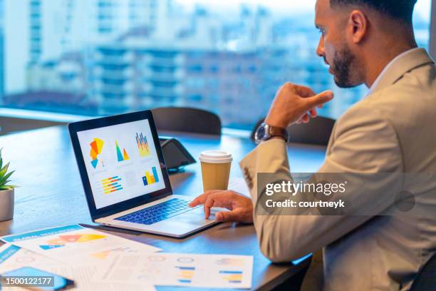 businessman using a laptop with financial data with graphs and charts on a laptop computer. - screen dashboard analytics stockfoto's en -beelden