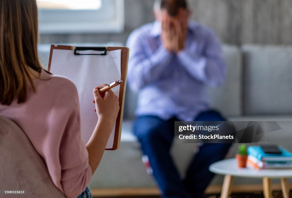 Close up of the psychologist's back while a man cries in the background