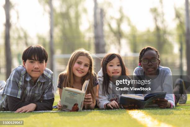 lovely pupils on reading on the grass - happy tween girls lying on grass stock pictures, royalty-free photos & images