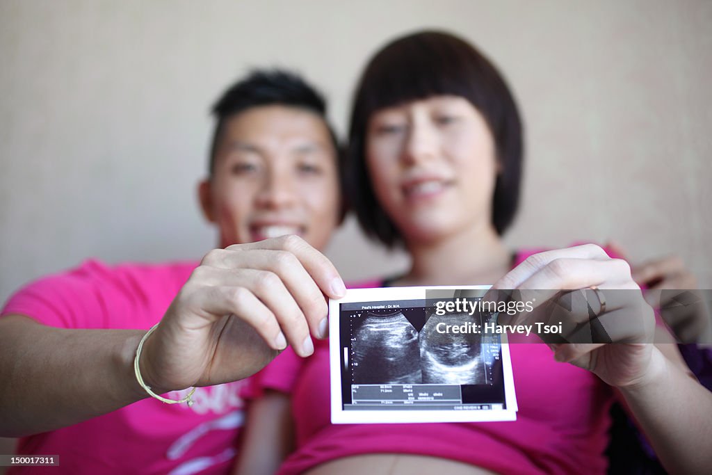 Smiling Asian couple holds sonogram