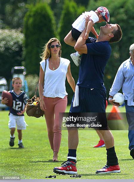 New England Patriots quarterback Tom Brady kisses his son, Benjamin, as his other son John, left, walks with Brady's wife, Gisele Bundchen, at the...