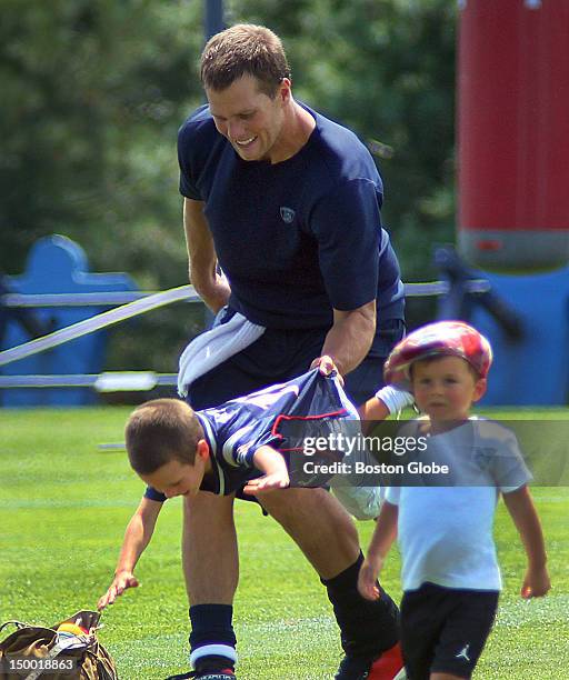 New England Patriots quarterback Tom Brady picks up his son, John, by the shirts as his other son, Benjamin, right, walks away at the end of...