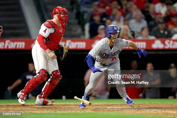 Michael Busch of the Los Angeles Dodgers connects for an RBI single as Chad Wallach of the Los Angeles Angels looks on during the eighth inning of a...