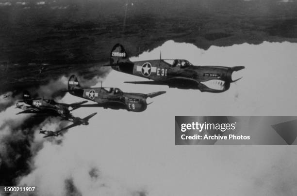 Curtiss P-40 Warhawk fighter aircraft flying in formation, the lead fighter painted with a 'shark mouth' image, in the skies over Selfridge Field in...