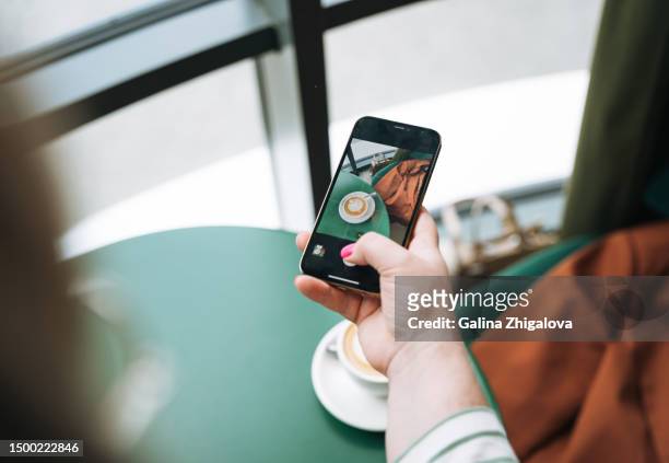 crop photo of young woman taking photo on her smartphone of coffee on table in cafe - table of content stock pictures, royalty-free photos & images