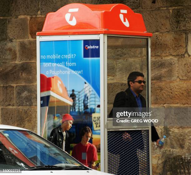 Man walks past a Telstra public phone box in Sydney on August 9, 2012. Australia's dominant telecom company Telstra posted a 5.4 percent jump in...