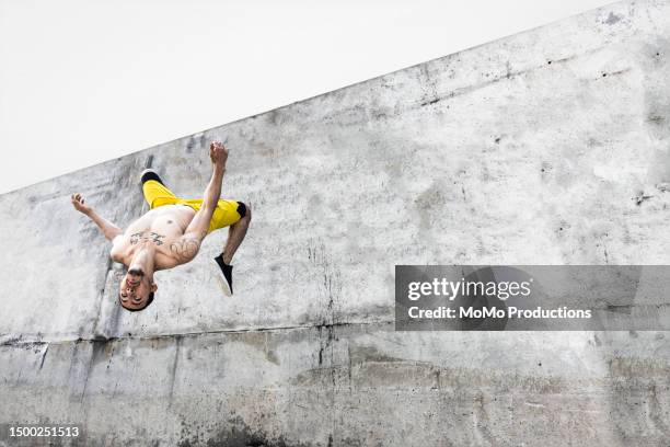 male athlete doing backflip off of concrete wall - backflipping fotografías e imágenes de stock