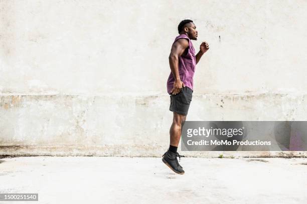 male athlete jumping in front of concrete background - black male bodybuilders foto e immagini stock