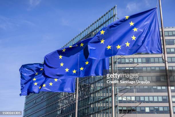 european union flags waiving in front of charlemagne building - comisión europea fotografías e imágenes de stock