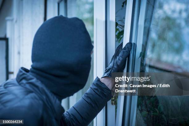 burglar trying to open a window - burgler stock-fotos und bilder