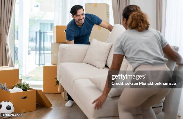 young couple moving sofa into new home - household equipment stock pictures, royalty-free photos & images