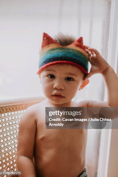 toddler boy sitting on a chair touching the crown on his head - mililani stock-fotos und bilder