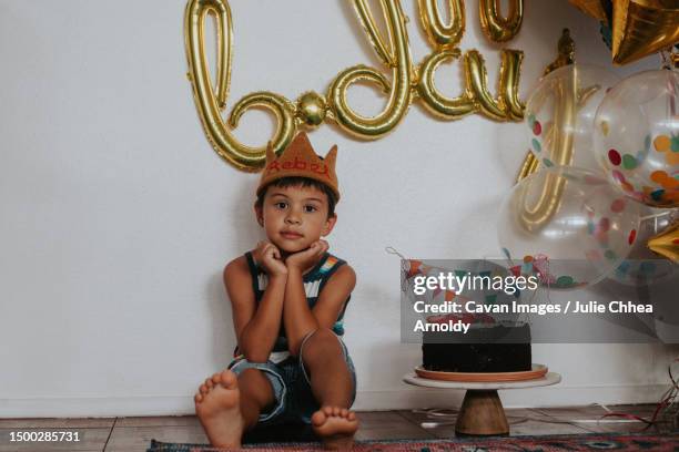 happy, young multiracial asian boy sitting with balloons and a c - mililani stock-fotos und bilder