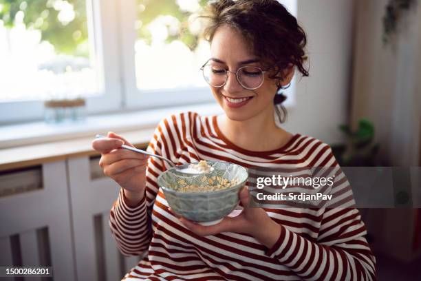 joven mujer caucásica tomando un desayuno de avena - gachas de avena fotografías e imágenes de stock