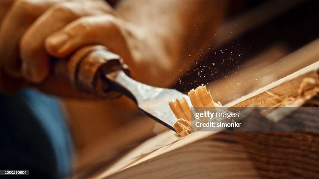Carpenter shapes wood with chisel