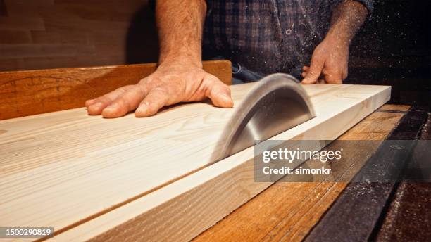 male carpenter's hands cutting wooden plank - table saw stock pictures, royalty-free photos & images