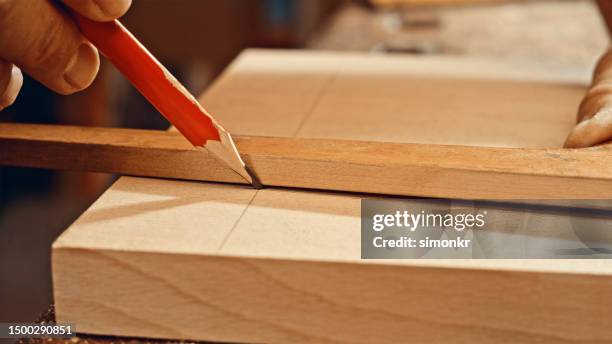 male carpenter's hand drawing on wooden plank - timmeren stockfoto's en -beelden
