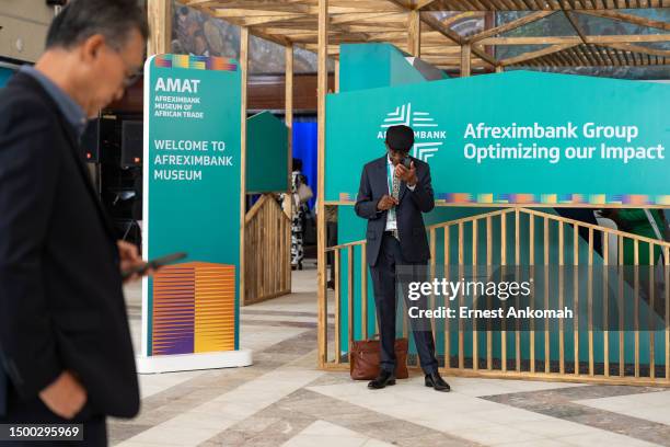 Two men use their smartphones during a coffee break at the African Export-Import Bank Annual Meeting on June 18, 2023 at the Accra International...