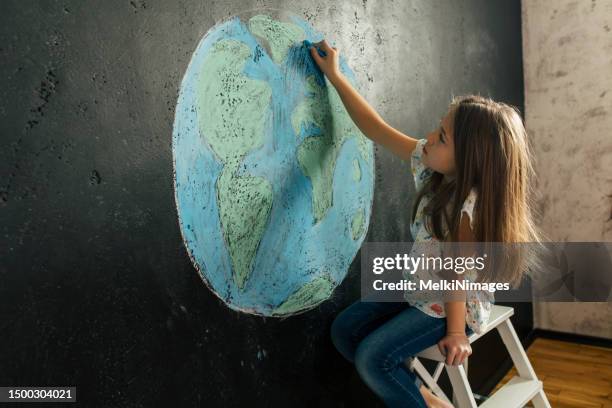 niña dibujando la forma del planeta tierra con tizas de colores - chalk art equipment fotografías e imágenes de stock