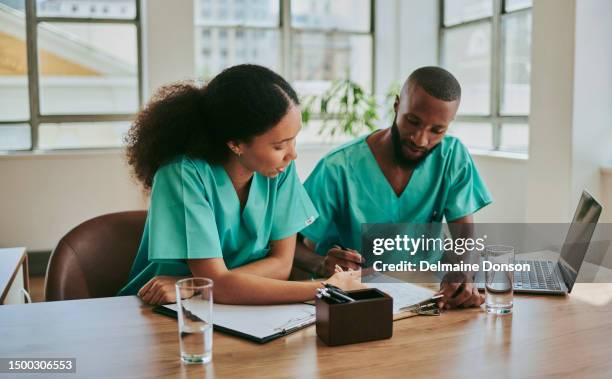 two nurses are sitting and going through paperwork at their desks. stock photo - clipboard and glasses stock pictures, royalty-free photos & images