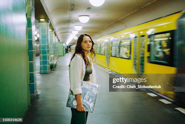 ビニールレコードを持つ駅で地下鉄を待つ女性 - アナログ ストックフォトと画像