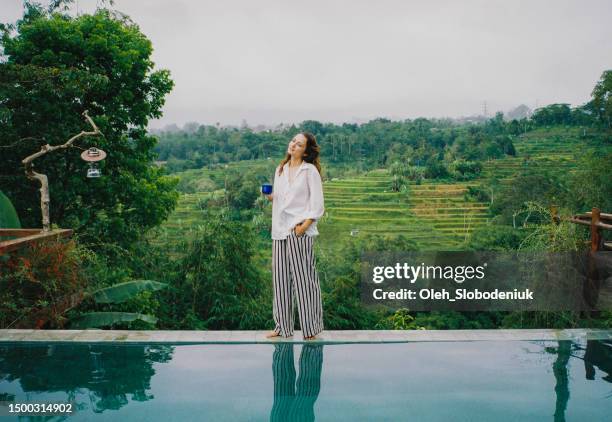 woman drinking coffee in the morning near the pool on bali - coffee perfection stock pictures, royalty-free photos & images