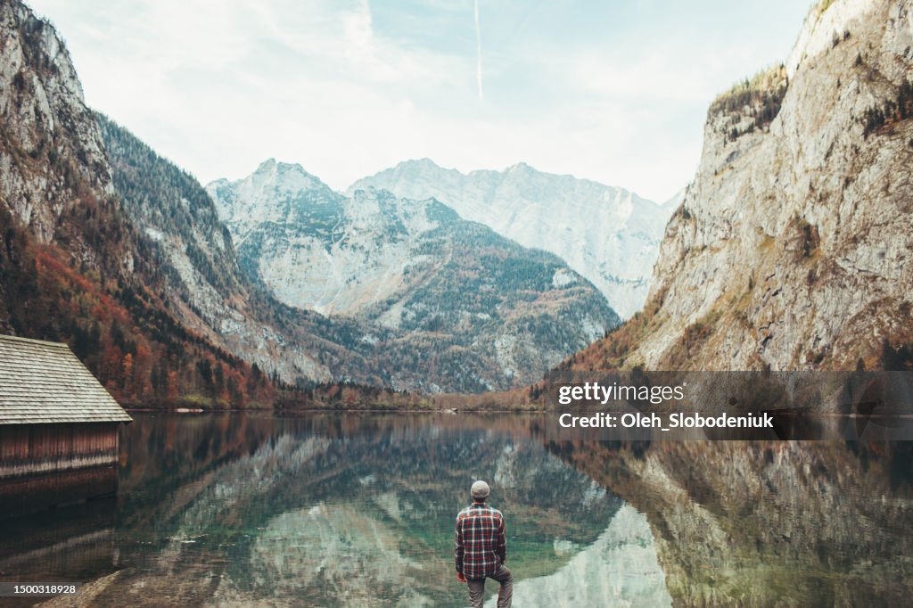 Mann, der auf den Königssee schaut und den Blick auf die bayerischen Alpen genießt