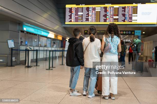 mutter und kinder, die auf die ankunfts- und abreisetabelle schauen - ankunfts und abfahrtstafel stock-fotos und bilder