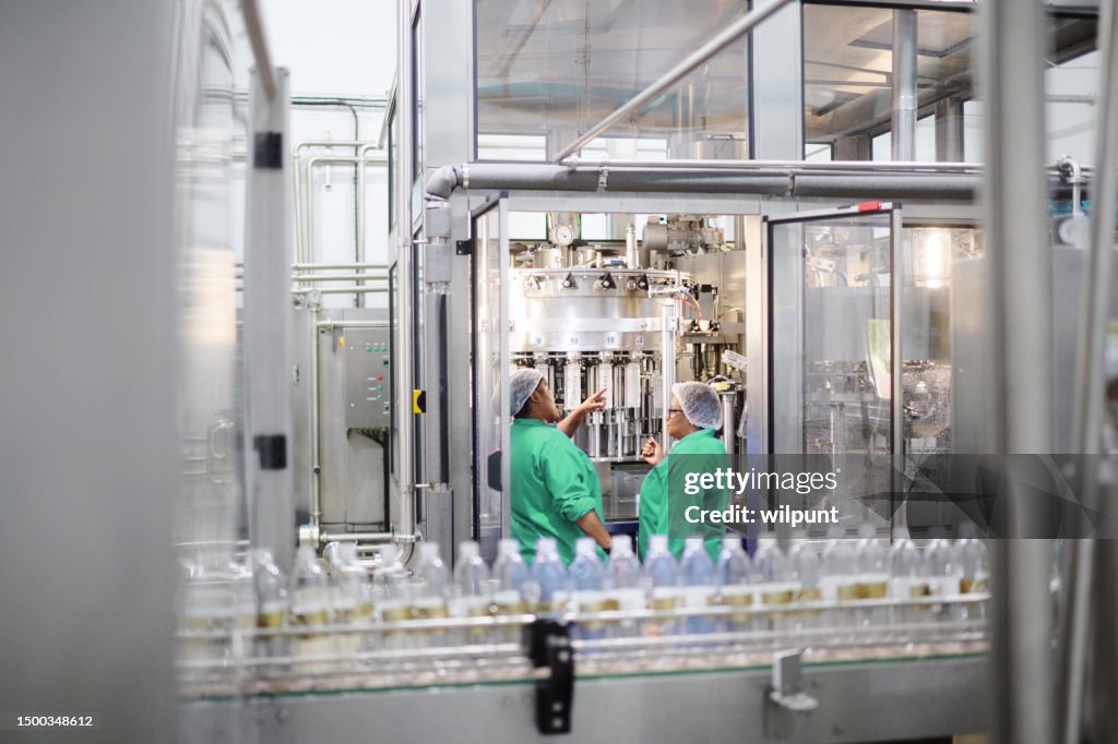 水瓶詰め工場の自動液体充填機の2人の女性オペレーター