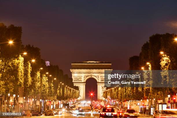 view along the champs elysee to arc de triomphe at night - avenue des champs elysees stock pictures, royalty-free photos & images
