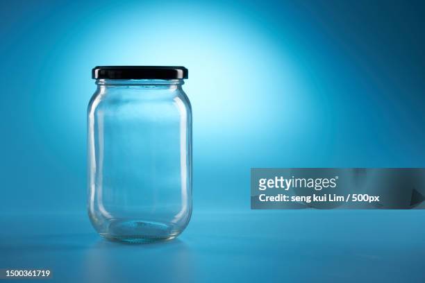 close-up of empty glass bottle against blue background - キャニスター　ガラス ストックフォトと画像