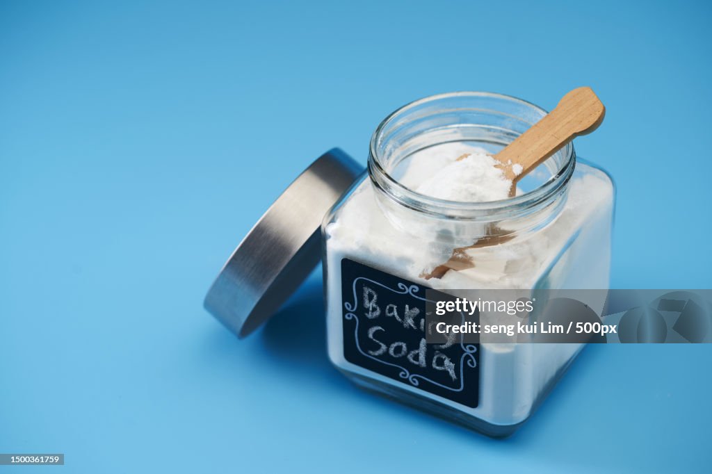 Close-up of baking soda in jar on table against blue background