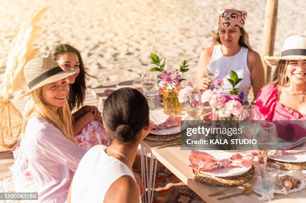 women chatting sitting on a luxury table on the beach - picknick edel stock-fotos und bilder