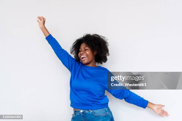 carefree afro woman with arms outstretched standing against white background - 長袖 ストックフォトと画像