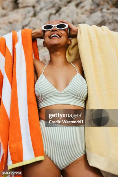 woman in bikini standing with towels at beach - striped towel stock pictures, royalty-free photos & images