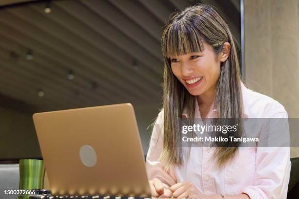 businesswoman having an online meeting in a stylish office cafeteria - makiko tanigawa stock-fotos und bilder