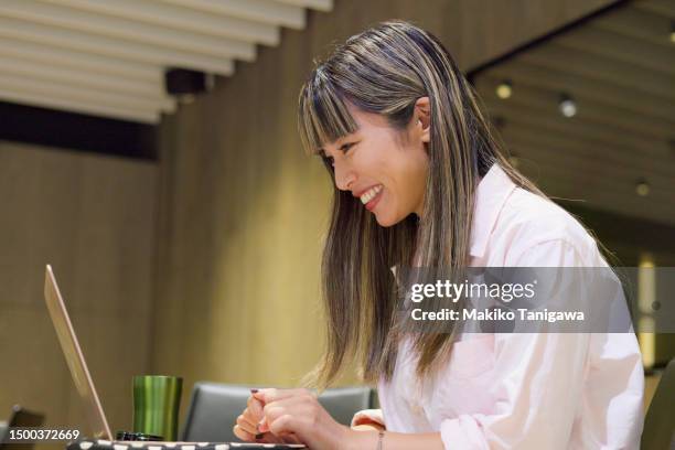 businesswoman having an online meeting in a stylish office cafeteria - makiko tanigawa stock-fotos und bilder