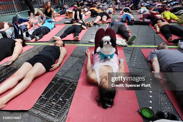Dog sits on its owner's belly during a mass yoga session on International Yoga Day in Times Square on June 21, 2023 in New York City. Thousands of...