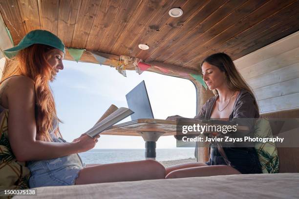 two female friends relaxing in camper van on the beach - camper van imagens e fotografias de stock