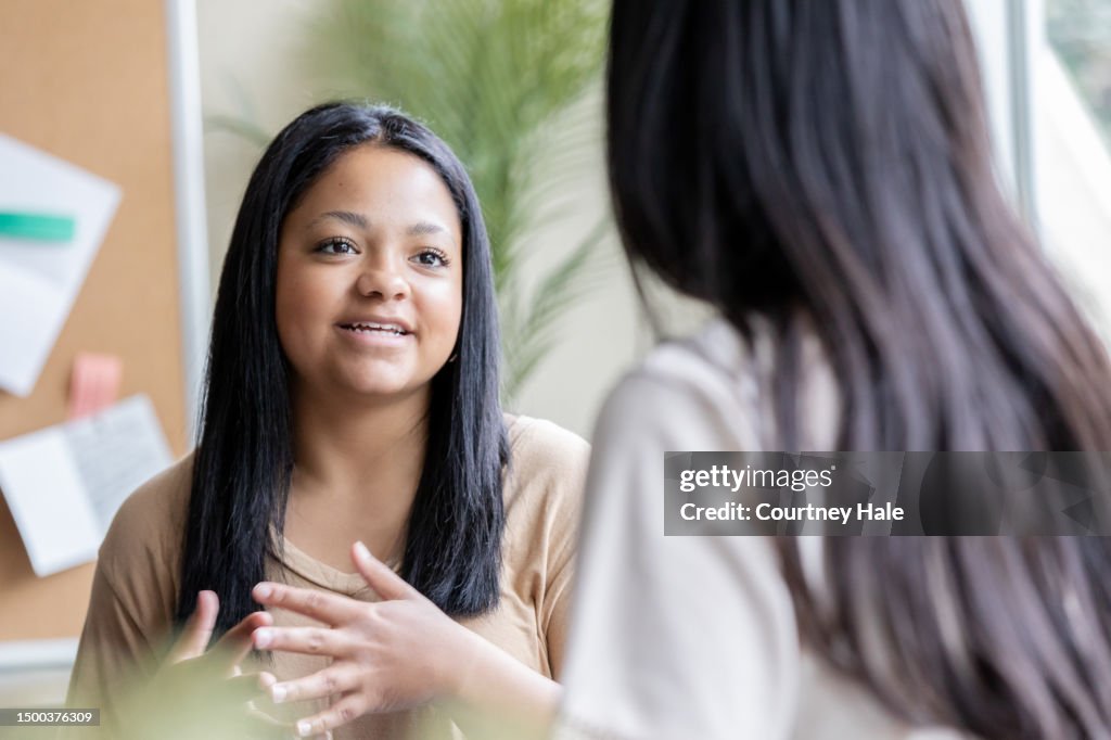 Teenage girl meets with teacher or guidance counselor in school office