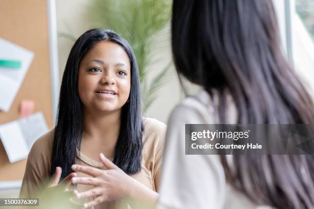 teenage girl meets with teacher or guidance counselor in school office - student advisor stock pictures, royalty-free photos & images