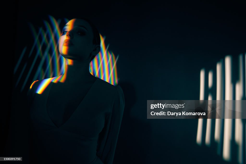 A young woman stands on a black background and looks away, waves of WiFi or wireless Internet pass through her. Technological concept and 5G technologies.