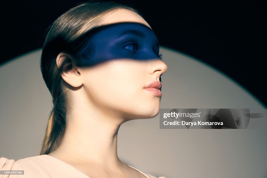 A beautiful young woman with a colored blue filter on the eyes, the concept of dreams, aromatherapy, disguise, privacy and planning.